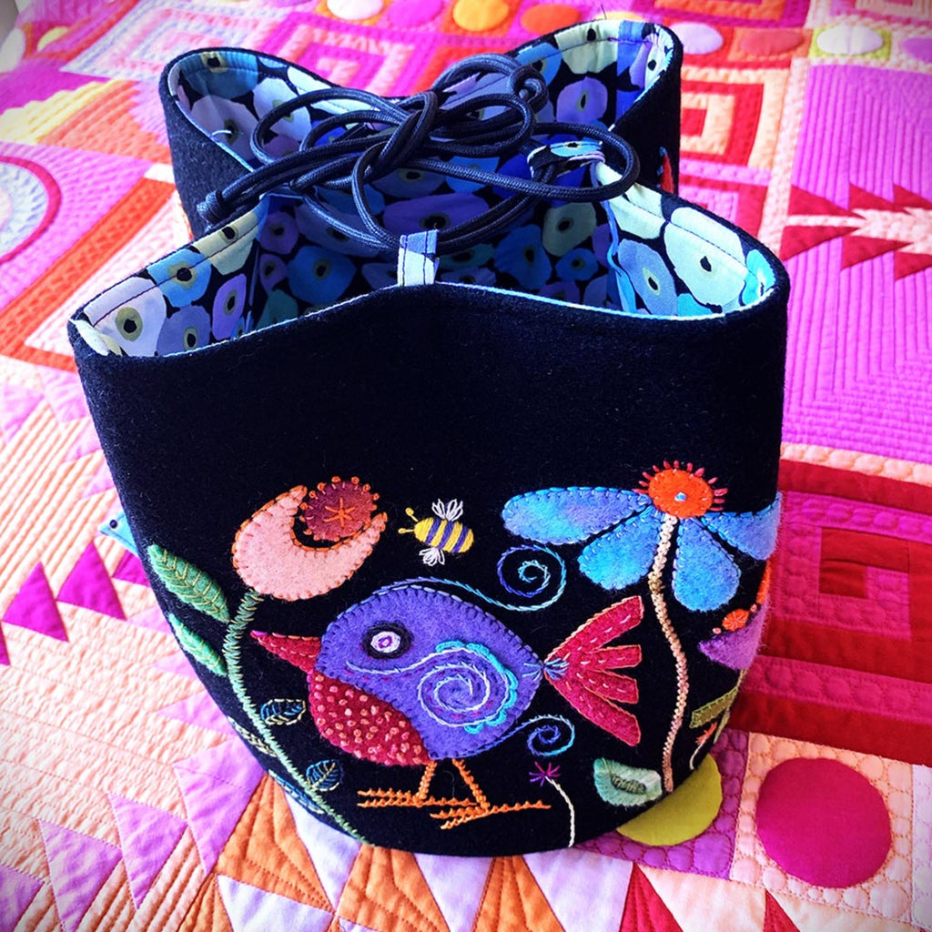 Decorative fabric basket with colorful bird and floral patterns on a quilted background.