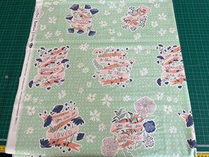 Fabric with decorative text and floral patterns on a green background