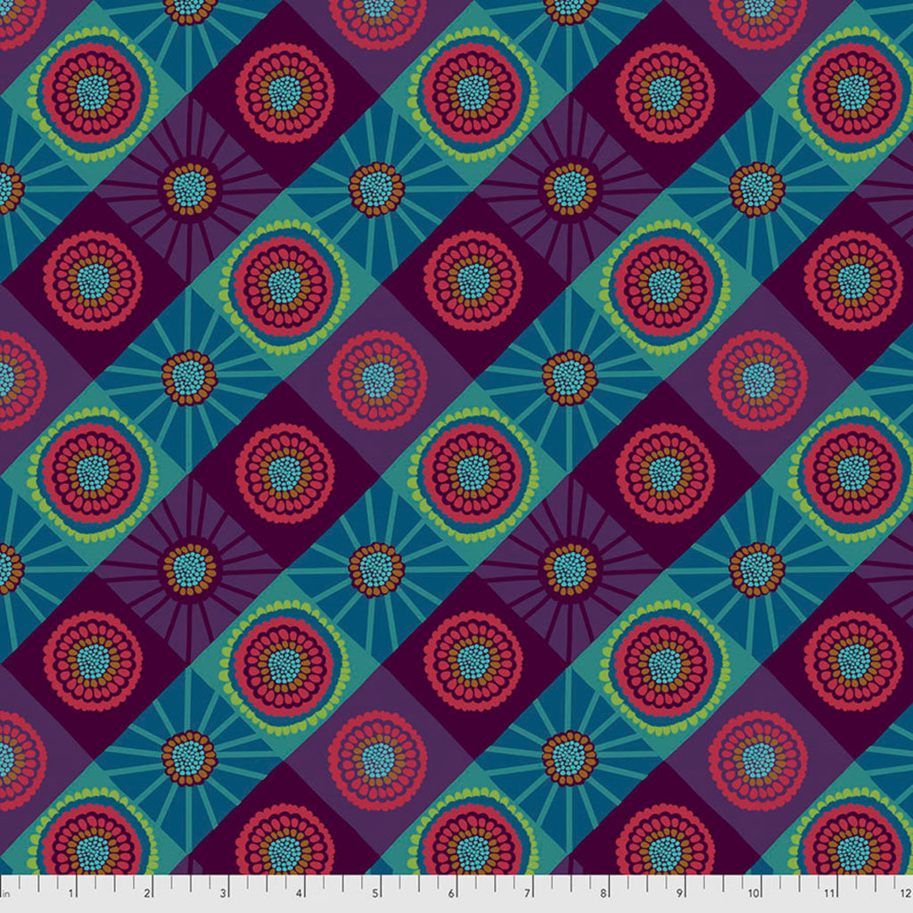 A piece of fabric featuring a geometric pattern with brightly colored circles and dots, predominantly in shades of blue and green, with a mountain-like border design.