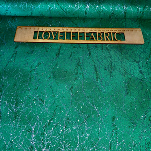 A piece of green fabric with a metallic texture featuring a diamond dust design, with the brand 'Love the Fabric' imprinted on it.